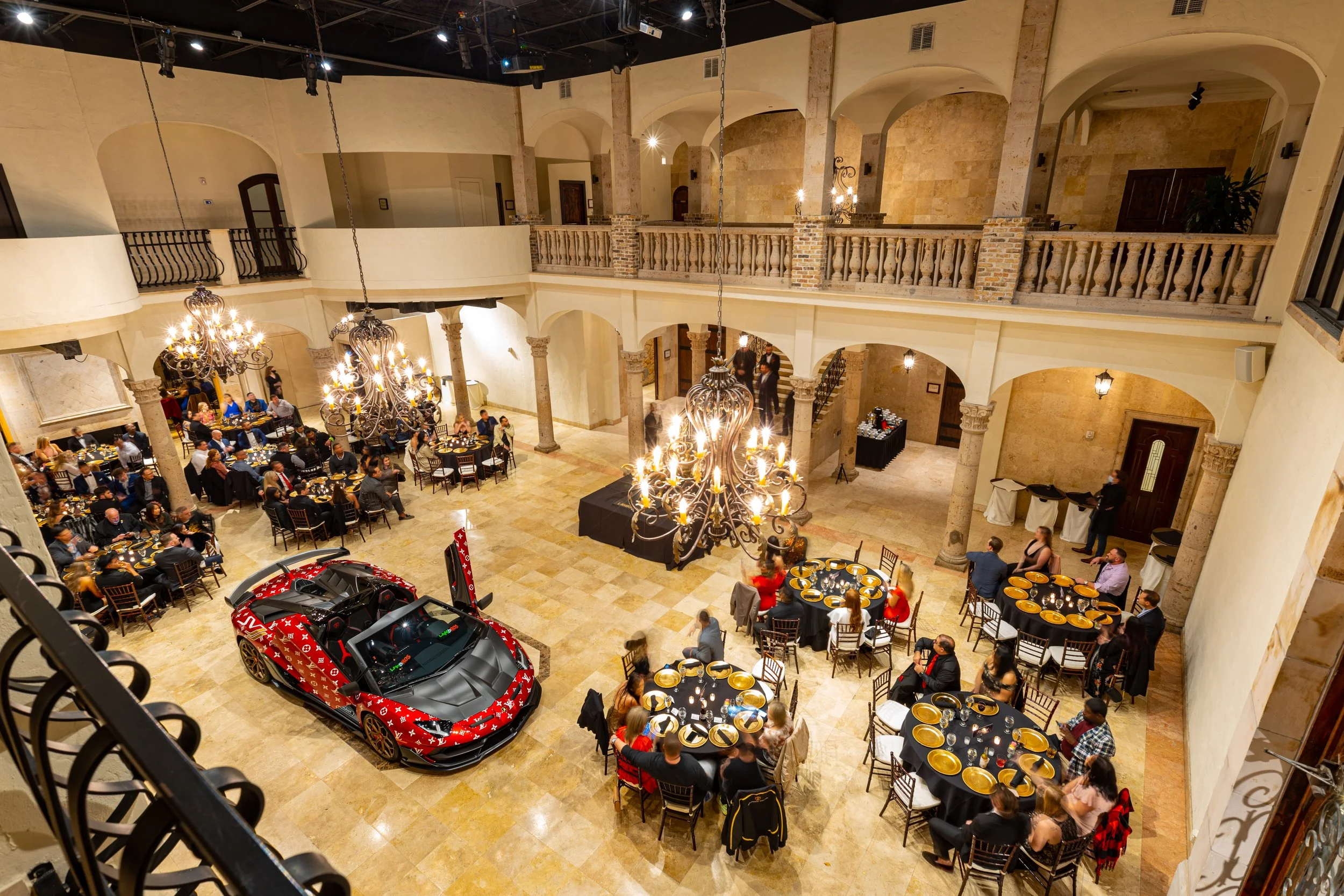 Corporate reveal dinner in the courtyard with round tables beneath the chandeliers at The Bell Tower on 34th