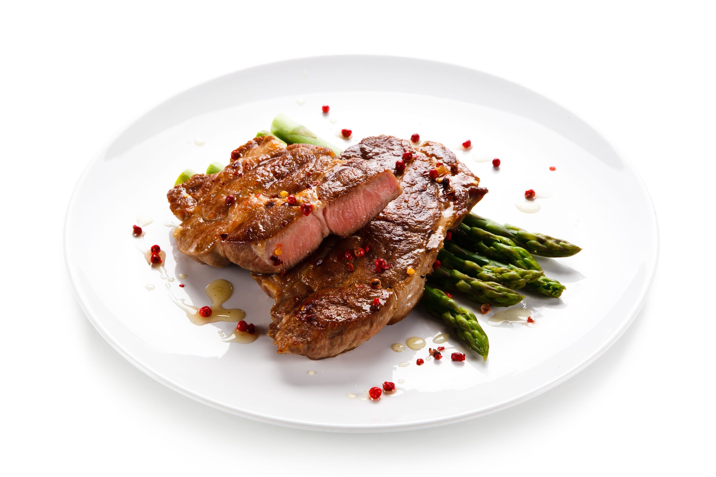 Plated entrée from the in-house kitchen at The Bell Tower on 34th: sliced grilled beef over asparagus with pink peppercorns