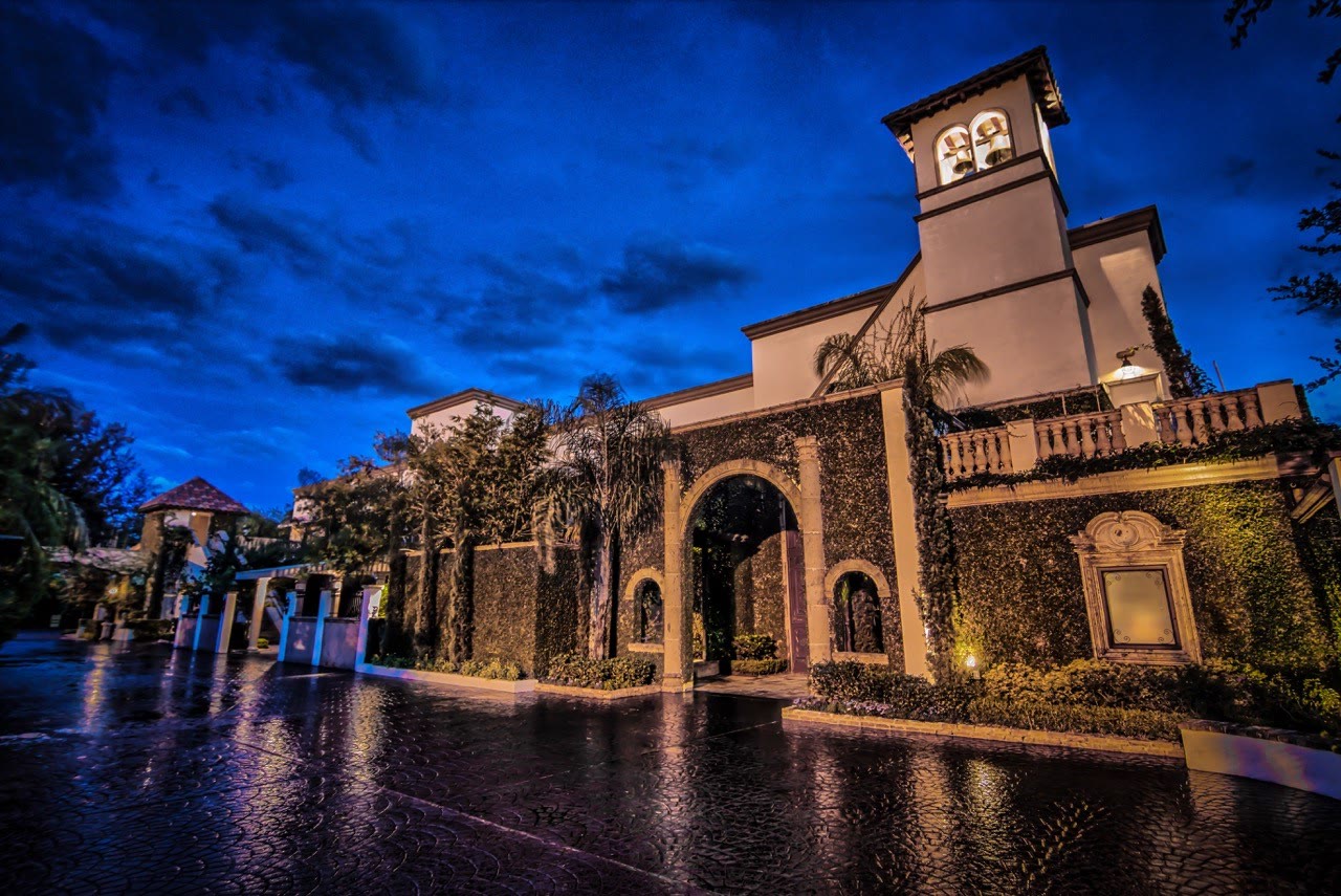 The Bell Tower on 34th at dusk, warm-lit arches reflected in water